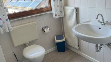 A bathroom with a toilet, sink, and window with solar panels outside.