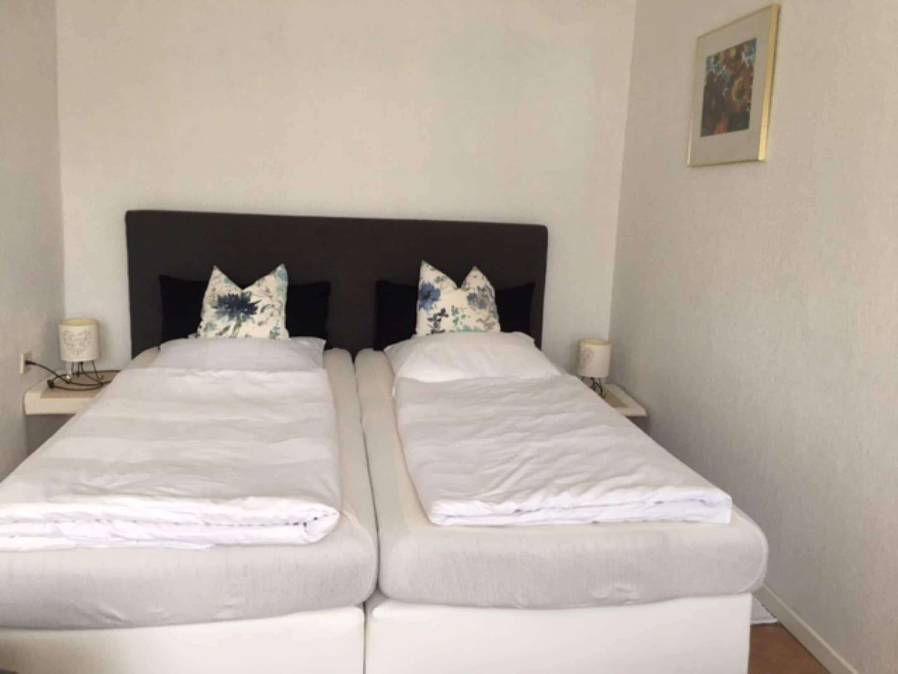 A double bed with a dark headboard, two bedside tables with lamps, and a framed picture on the wall.