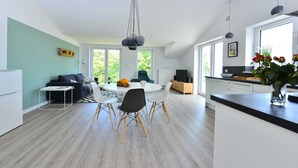 Una cocina moderna con comedor, ventanas amplias y vistas a zonas verdes.