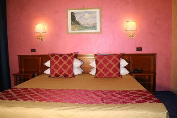 A hotel room with a large bed, two bedside tables, a nightstand, a painting on the wall, and two wall-mounted lamps. - Hotel Abacus (Porto Mantovano)