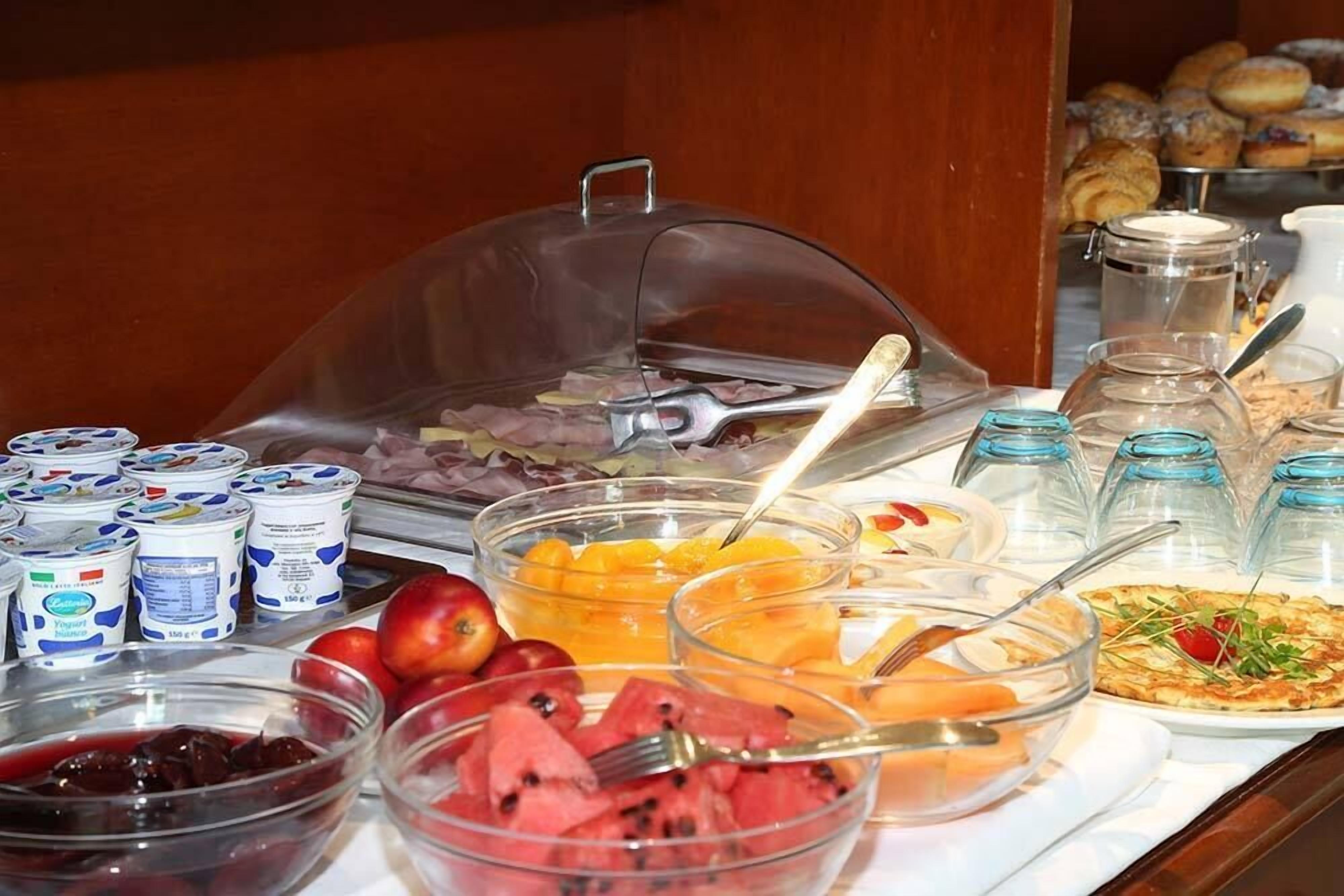 Un buffet proposant une variété d'aliments, notamment des fruits, des yaourts et des pâtisseries.