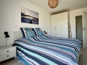 A bedroom with a bed, a nightstand, a wardrobe, and a painting on the wall.