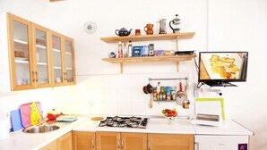 Una cocina con armarios de madera, cocina a gas, un lavamanos y un refrigerador pequeño.