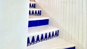 Una escalera con paredes blancas y escalones azules, que conduce a un techo de madera con vigas azules.