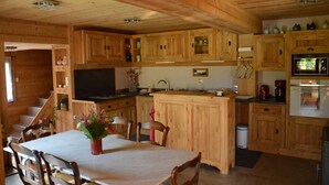 Ein Holzblockhaus mit Essbereich, Küche und Treppe.