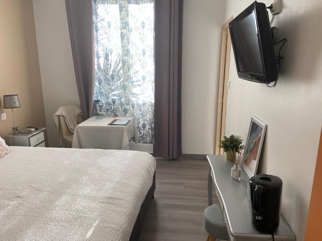 Une chambre d’hôtel avec un lit, un bureau, une télévision et une fenêtre avec des rideaux.