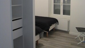 Un dormitorio con cama, armario, radiador y ventana.