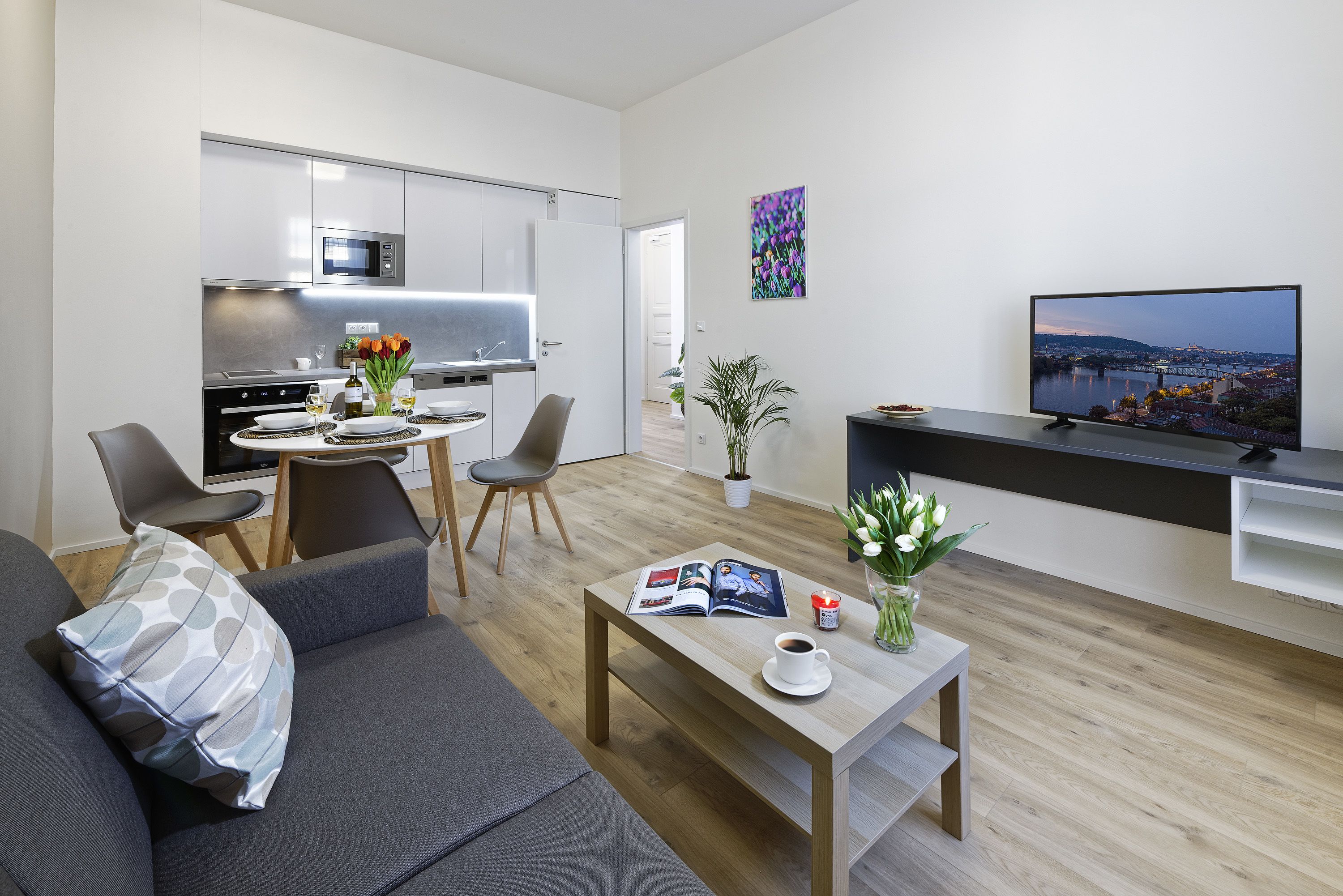 A modern living room with a sofa, coffee table, and a dining area with chairs and a table.