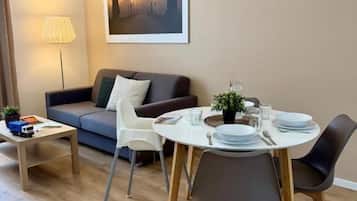 Una sala de estar moderna con sofá, mesa de comedor, sillas y una lámpara.