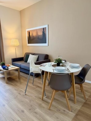 A modern living room with a sofa, dining table, chairs, and a lamp.