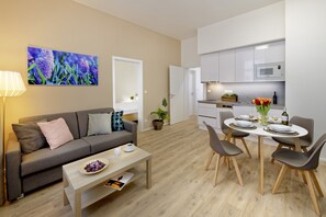 A modern living room with a sofa, coffee table, and dining area with chairs and a table. - DownTown Suites Jugoslavska (Prague)