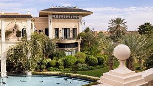 A luxurious villa with a swimming pool, surrounded by lush greenery and palm trees. - Palais Ronsard (Marrakech)