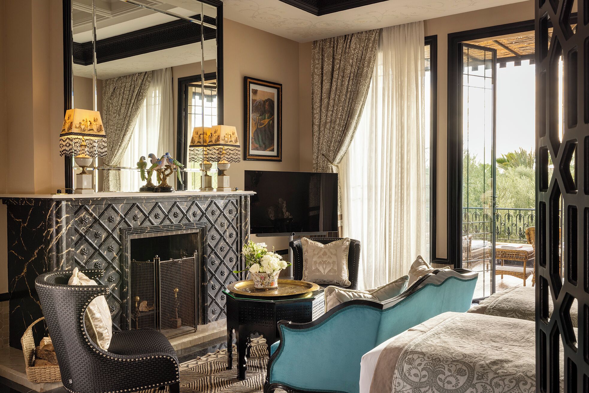 A room with a fireplace, a large mirror, a television, and a balcony with outdoor furniture.