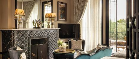 A room with a fireplace, a large mirror, a television, and a balcony with outdoor furniture.