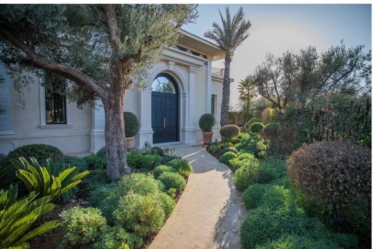 A well-maintained garden with a paved pathway leading to a building with a dark entrance door.