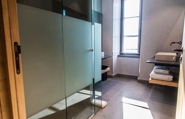 Een moderne badkamer met een glazen deur, een raam en een plank met handdoeken.