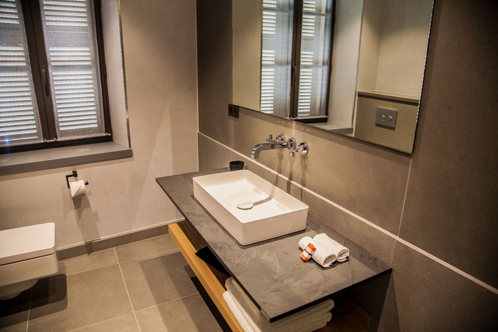 A modern bathroom with a rectangular sink, a mirror, and a towel rack.