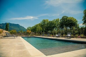 Une piscine avec des chaises longues, le tout surplombé par un paysage montagneux.
