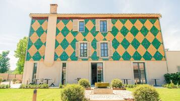A building with a distinctive diamond-patterned exterior, a central entrance, and a small garden area with seating.