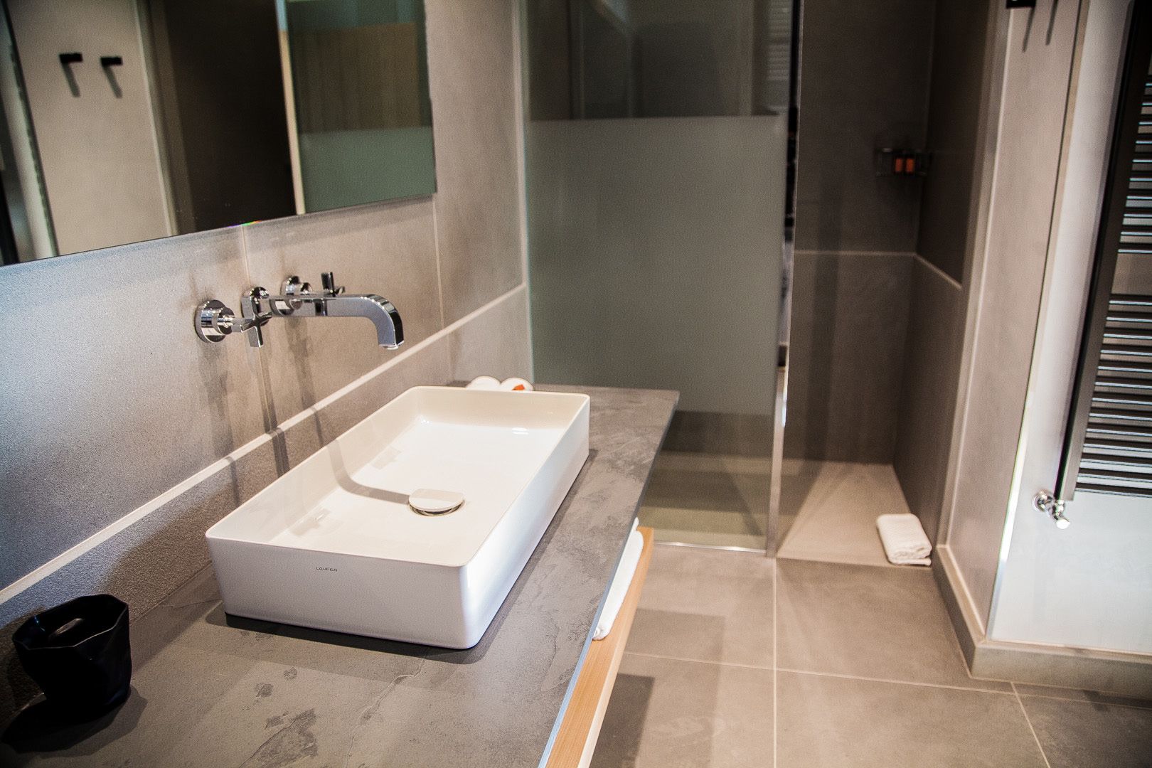 A modern bathroom with a rectangular sink, a mirror, and a shower area.