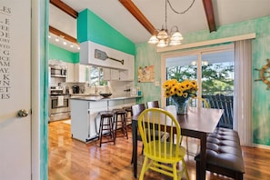 A kitchen with white cabinets, a central island, and a dining area with a yellow chair and a table.