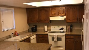 A kitchen with granite countertops, wooden cabinets, a stove, and a dishwasher. - Summer tenant special, 1 BR Condo with sparkling pool view!  RELAXATION IN AZ! (Phoenix)