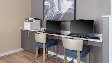 Um espaço de escritório moderno com uma mesa, duas cadeiras, um computador e uma impressora.