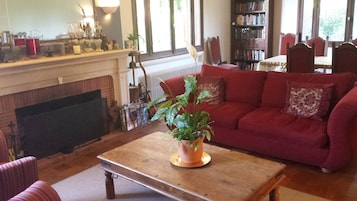 A cozy living room with a fireplace, a red sofa, a wooden coffee table, and a bookshelf filled with books.