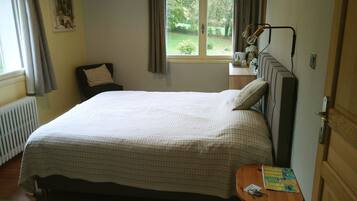 A neatly made bed with a patterned bedspread, a bedside table with a map and a key, and a window with curtains.