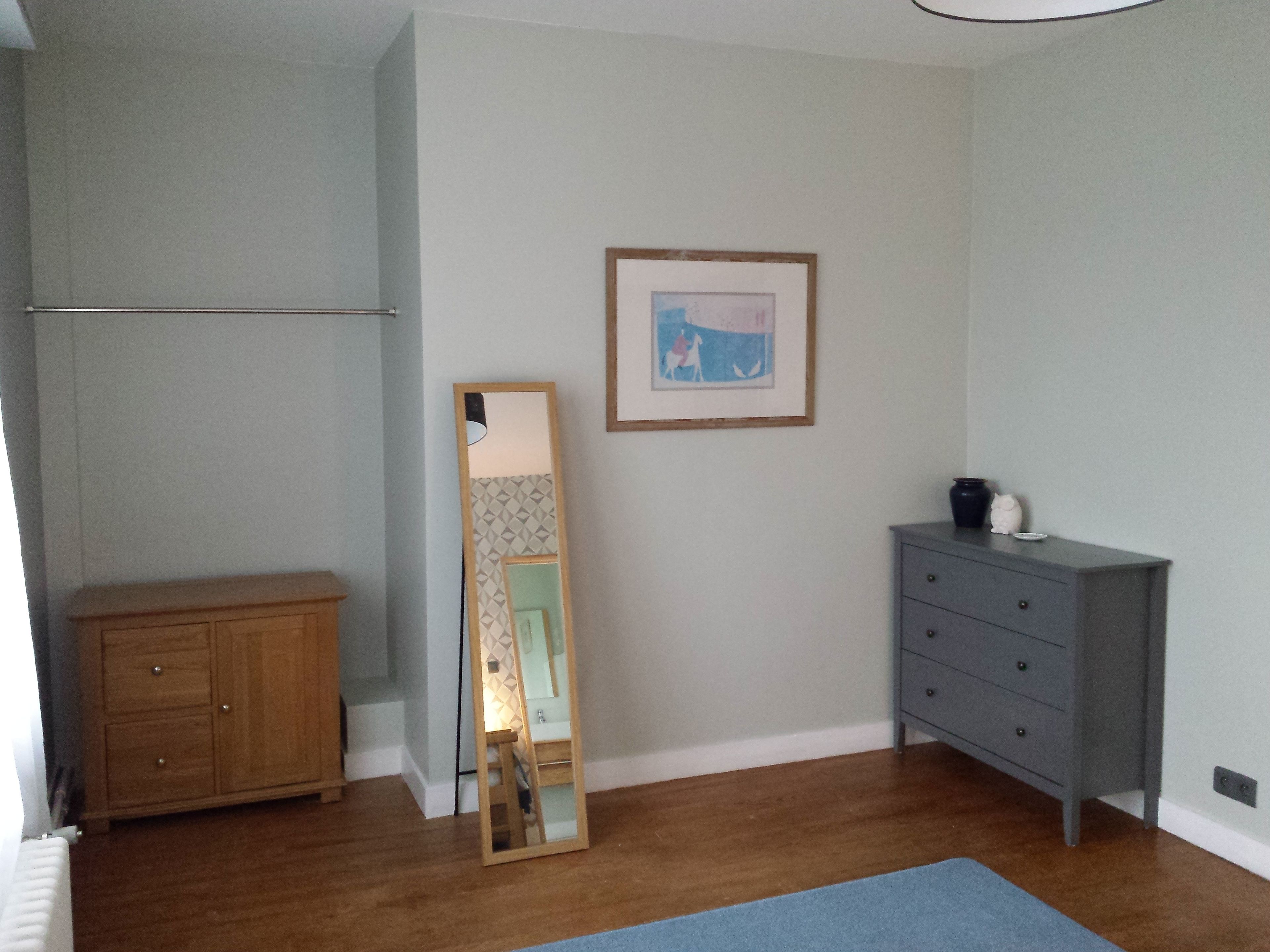 A room with a wooden cabinet, a dresser, a mirror, and a framed picture on the wall.