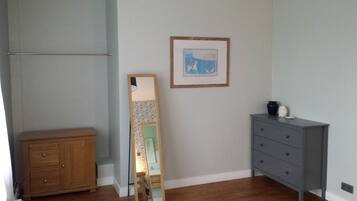 A room with a wooden cabinet, a dresser, a mirror, and a framed picture on the wall.