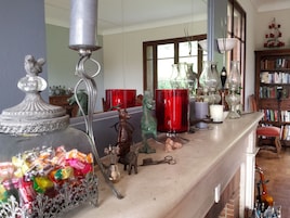 A cluttered shelf with various decorative items, including a glass jar filled with colorful candies, a metal candle holder, and a small figurine.