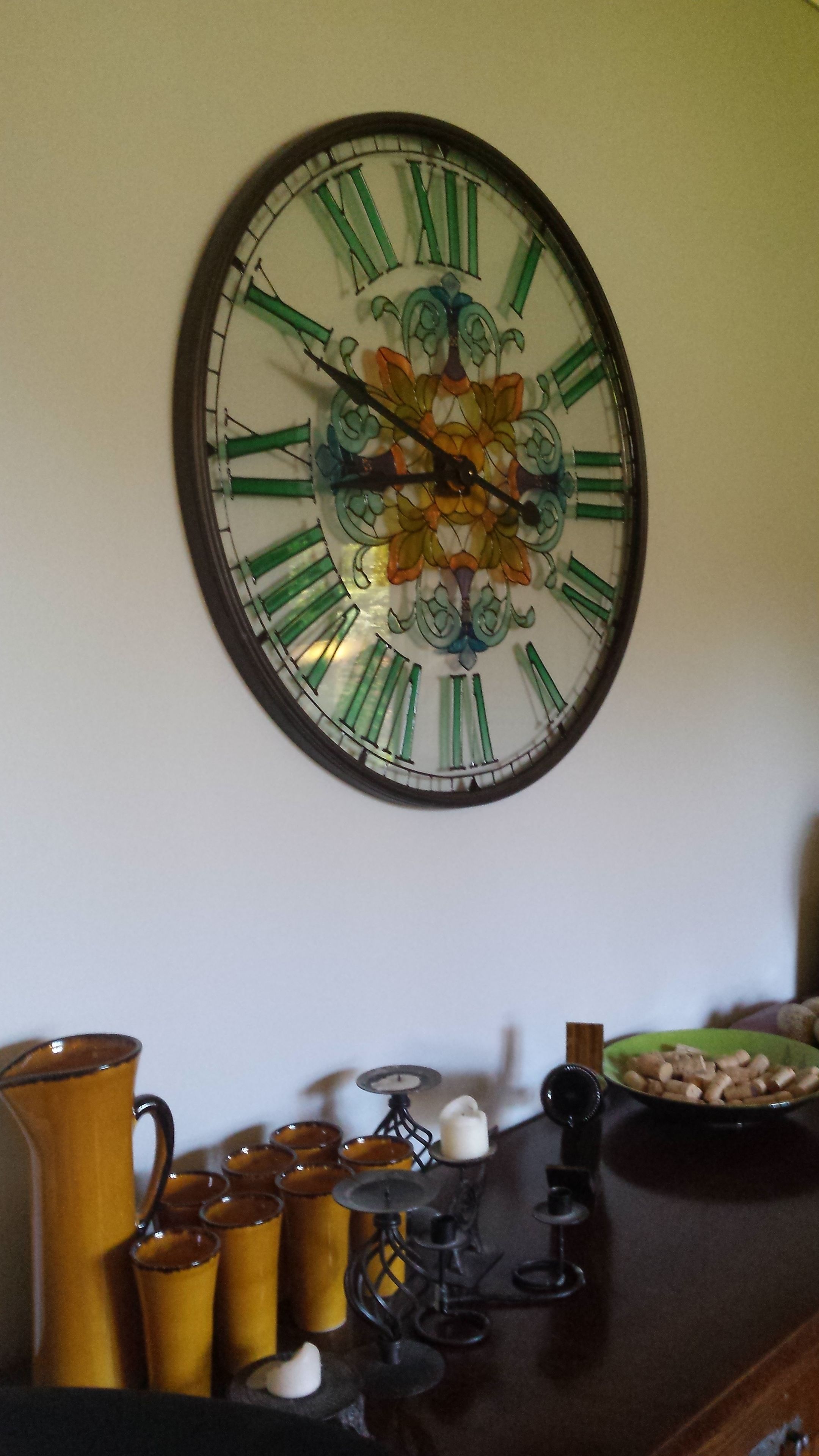Un reloj de pared con números romanos y un diseño floral.