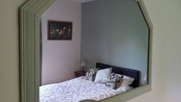 Un dormitorio con cama, mesita de noche, lámpara y un cuadro en la pared.