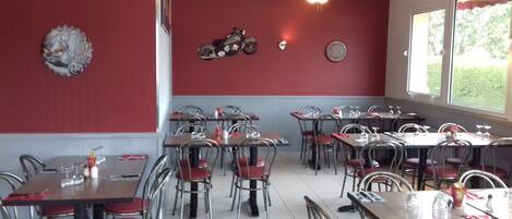 Ein Restaurantinneres mit roten Wänden, Metallstühlen und Tischen.