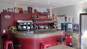 A bar area with a red counter, espresso machine, and various bottles. There are posters on the wall and a 'No Smoking' sign. - Hôtel Le Goas Plat (Paimpol)