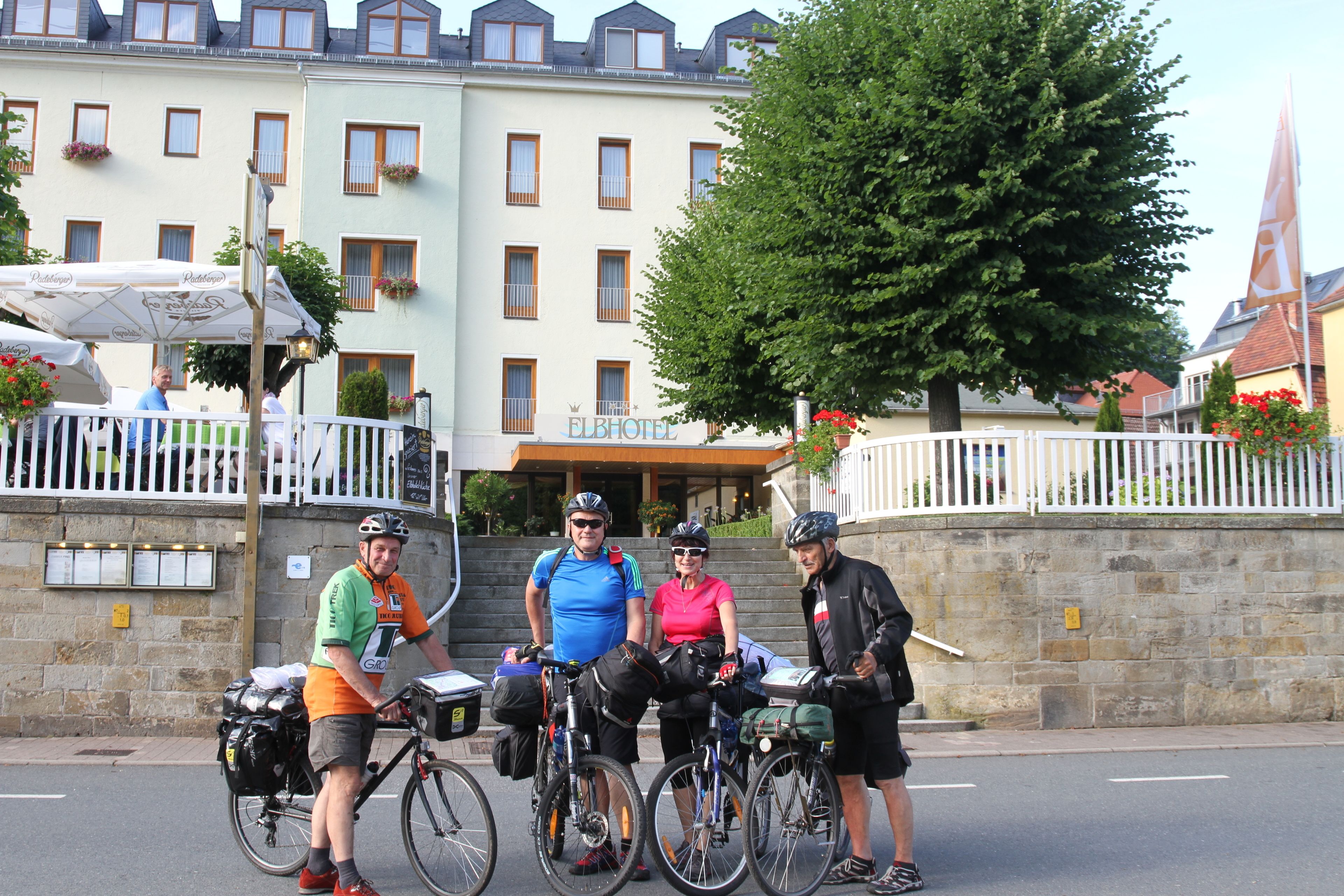 A group of cyclists standing in front of a building with a sign that reads "ELBHOF HOTEL".