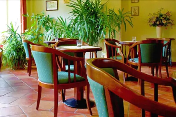 Un restaurante con sillas y mesas de madera, rodeado de plantas en macetas.