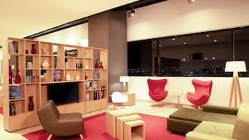Un salon moderne doté d’une bibliothèque, d’un téléviseur à écran plat et de sièges contemporains.