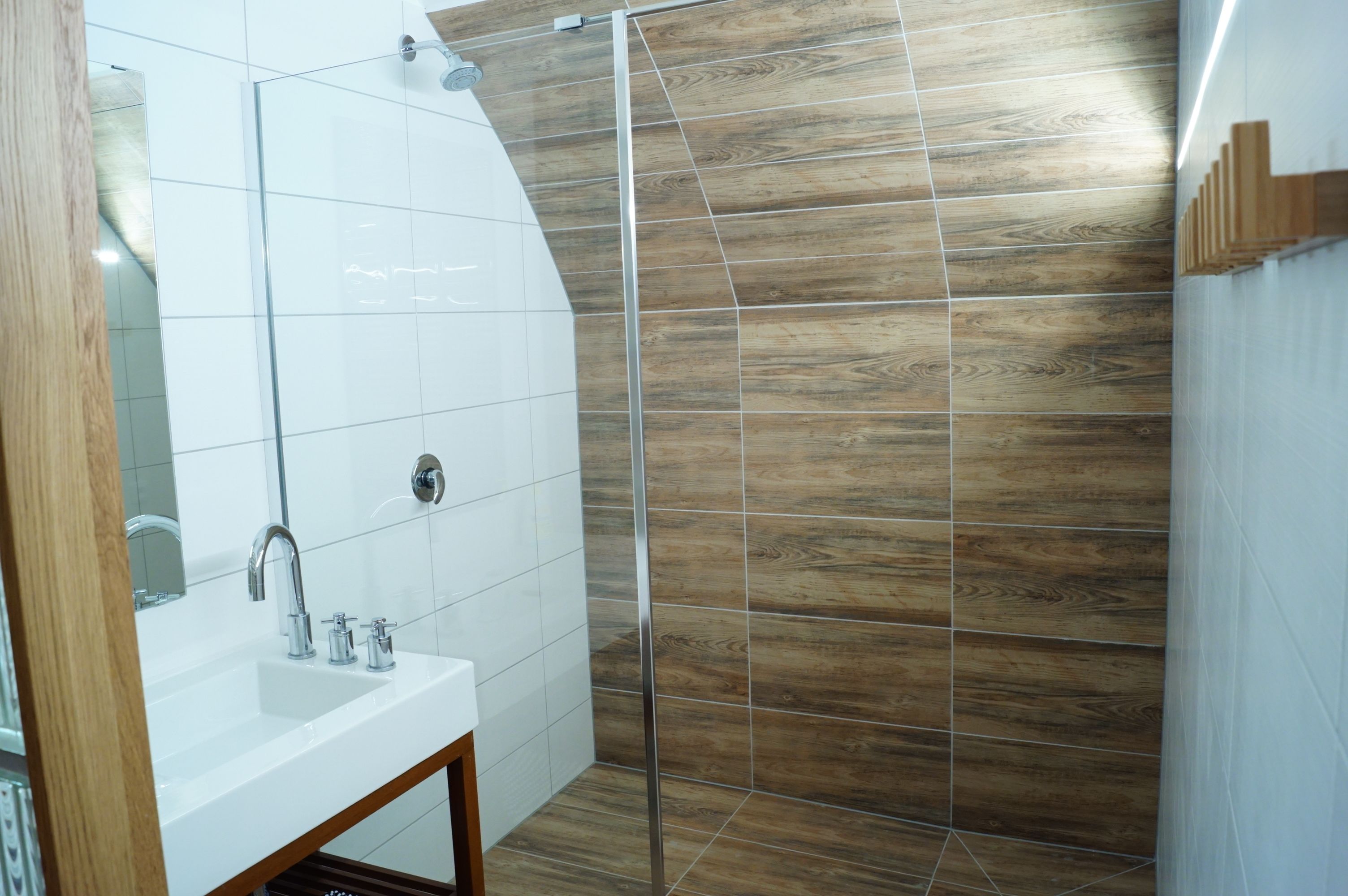 A modern bathroom with a white sink, mirror, and shower area.