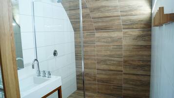 A modern bathroom with a white sink, mirror, and shower area.