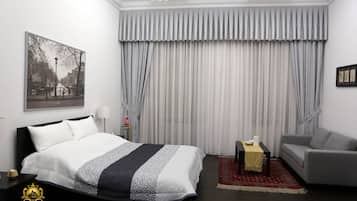 Ein Hotelzimmer mit Bett, Sofa, kleinem Tisch und großem Fenster mit Vorhängen.