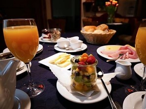 A breakfast setting with a fruit salad, bread, and a glass of orange juice on a table.