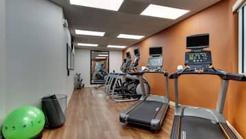 A gym with treadmills, exercise balls, and a mirror.