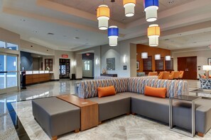 A modern lobby with a large sectional sofa, a wooden coffee table, and a marble floor. - Drury Inn & Suites Knoxville West (Knoxville)