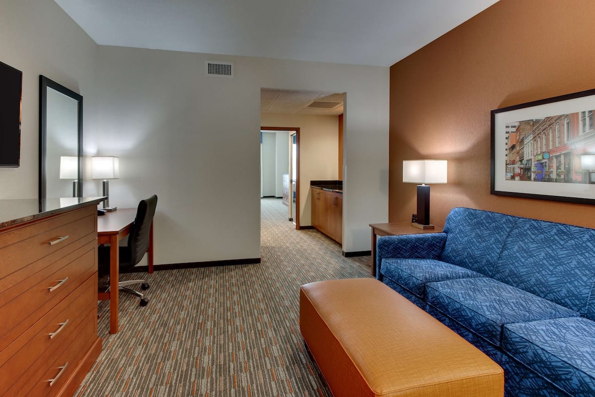 Une chambre d’hôtel équipée d’un bureau, d’une chaise, d’une commode, d’un canapé et ornée d’un tableau au mur.