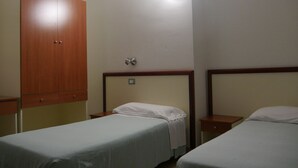 A hotel room with two single beds, a wooden wardrobe, a bedside table with a lamp, and a wall-mounted light fixture. - Hotel Risveglio (Castelfranco di Sotto)