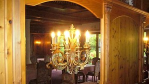 A wooden interior with a chandelier, dining table, and chairs.