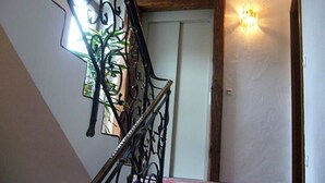 A staircase with ornate metal railings and a wall-mounted light fixture. - Alpenhotel Pfaffenwinkel (Peiting)