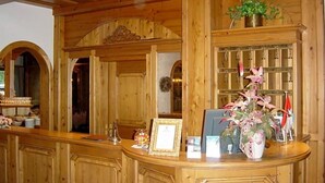 A reception area with wooden paneling, a reception desk, a framed certificate, and a potted plant.